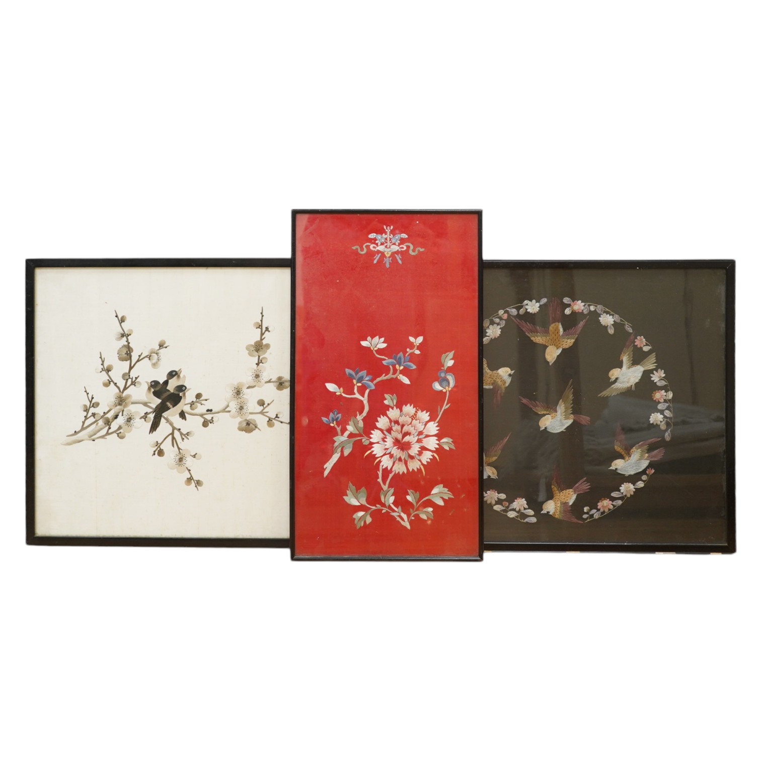 Two Chinese polychromed silk embroidered panels, early 20th century, one on a black silk ground of birds and flowers, the other on a red background of flowers and a monochrome silk embroidered panel of birds and flowers,